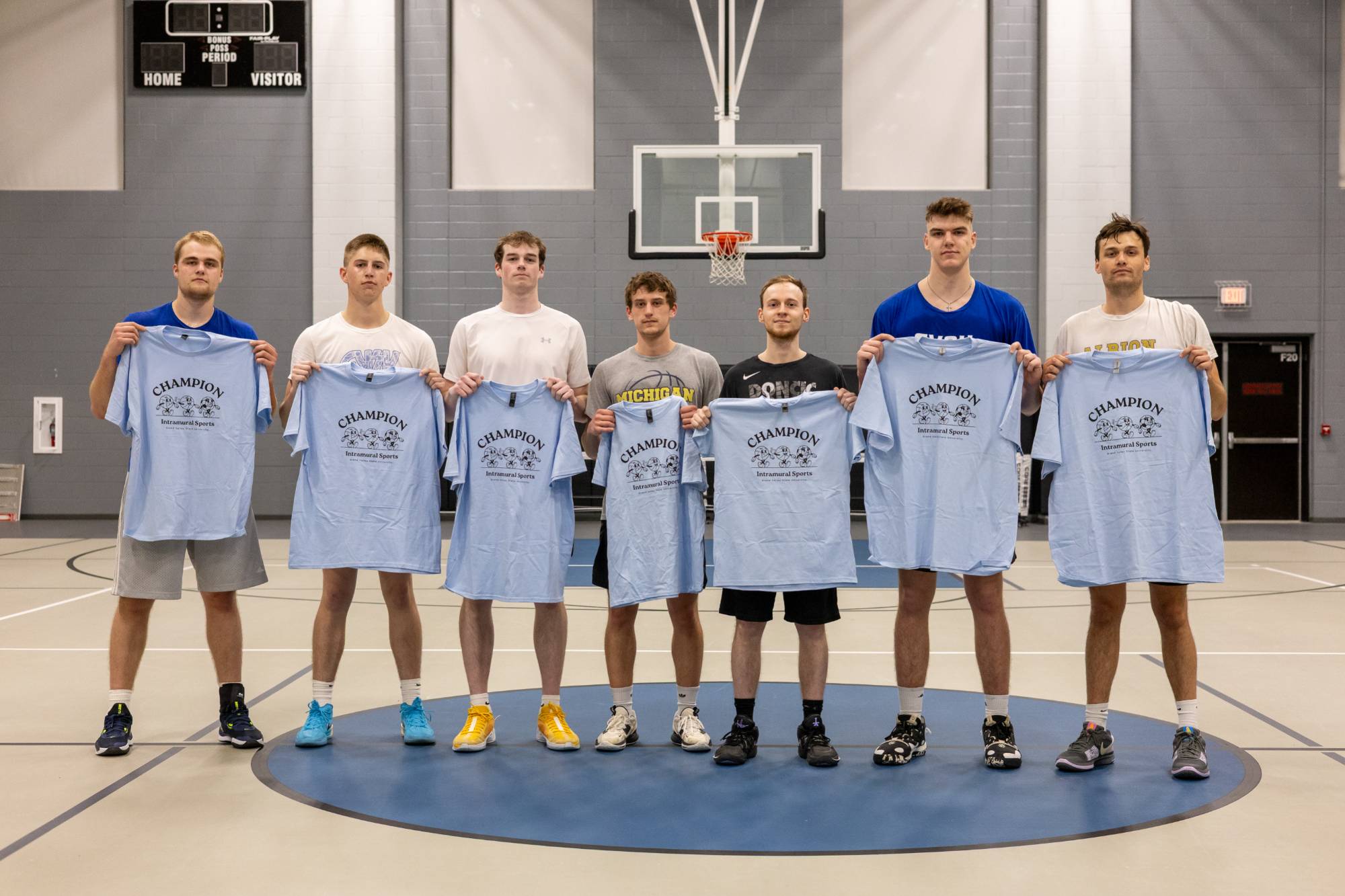 Grand valley students posing with championship t-shirt for winning the basketball bracket.